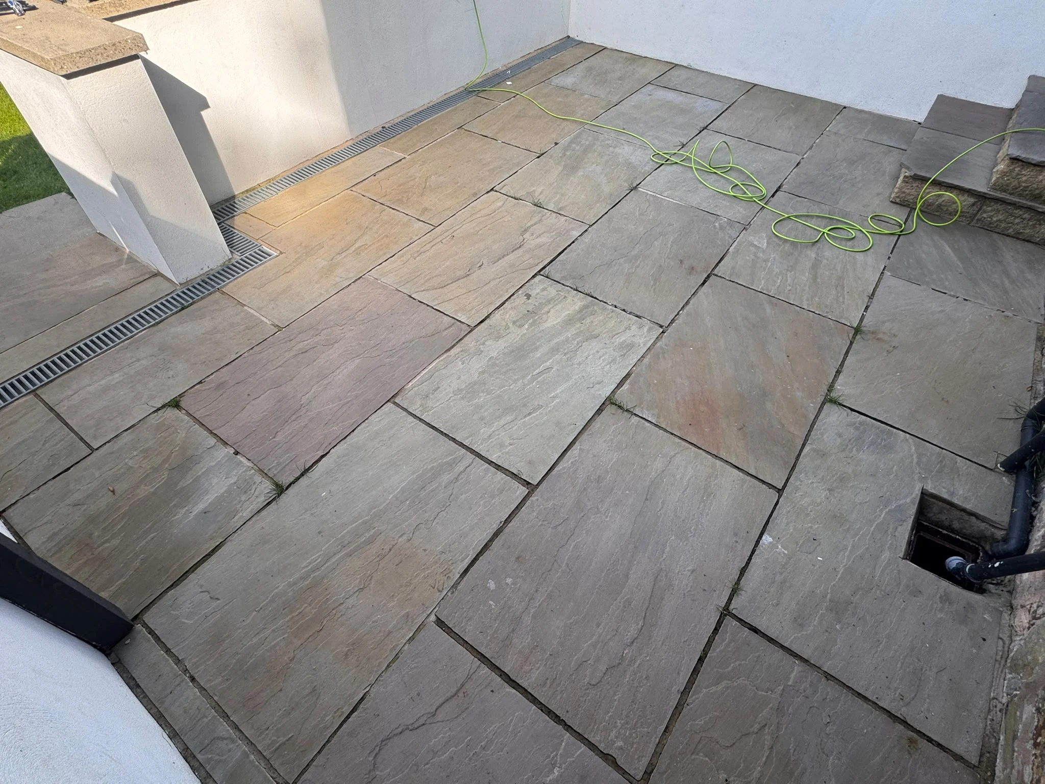 Stone courtyard patio before professional cleaning, with pressure-washing equipment visible