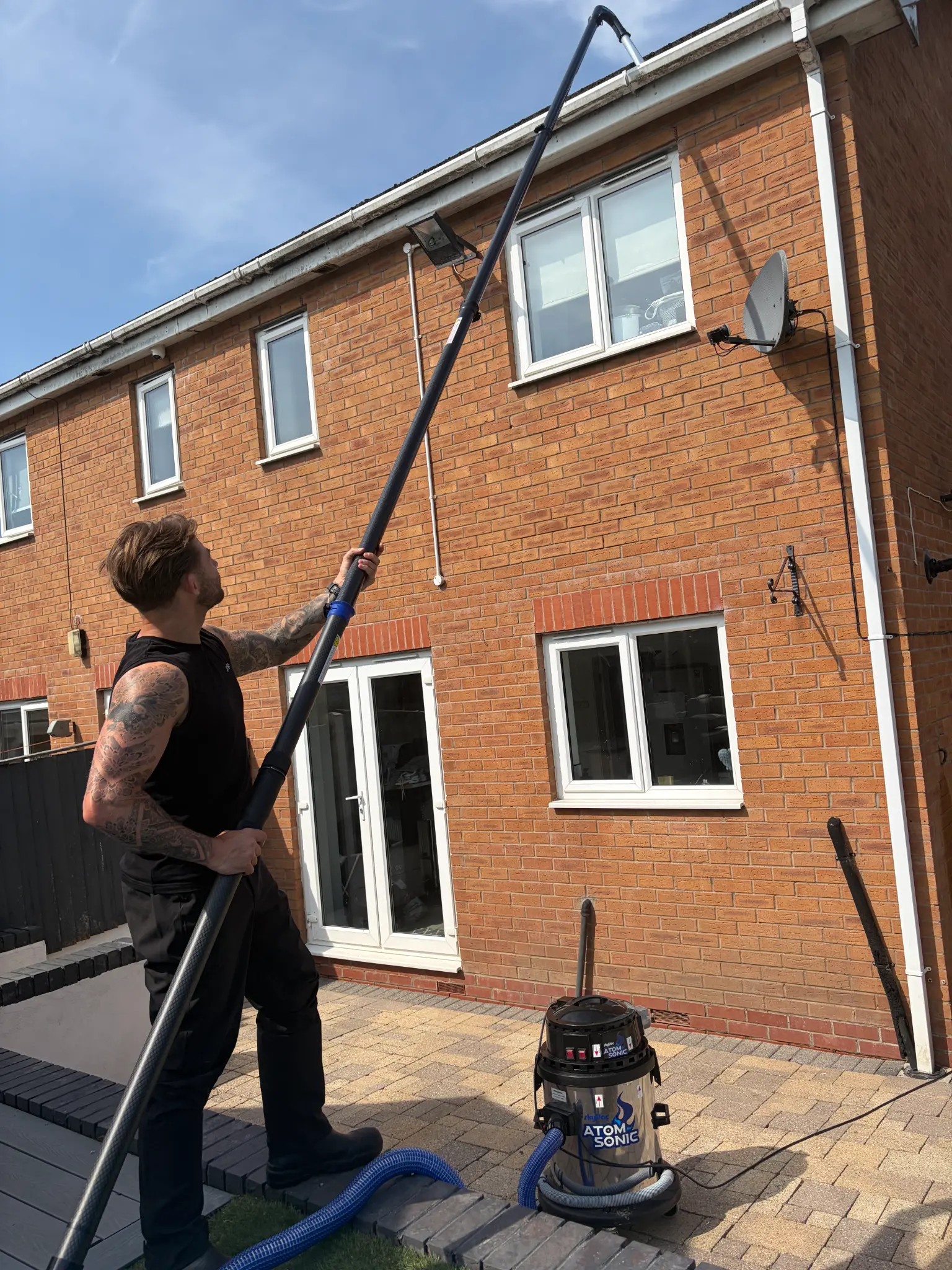 Technician using a gutter vacuum pole to clear a residential gutter