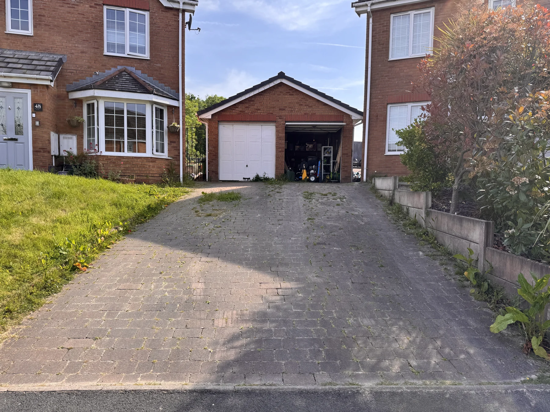 Weed-covered paved driveway before professional cleaning