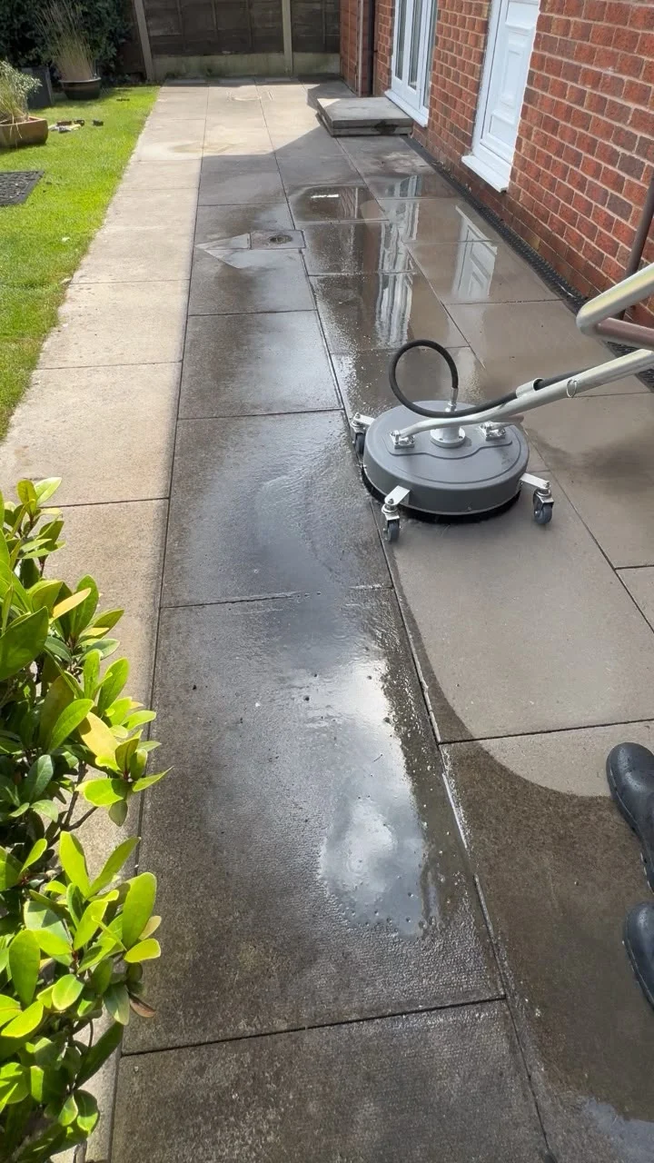 Surface cleaner restoring a residential patio beside a brick home