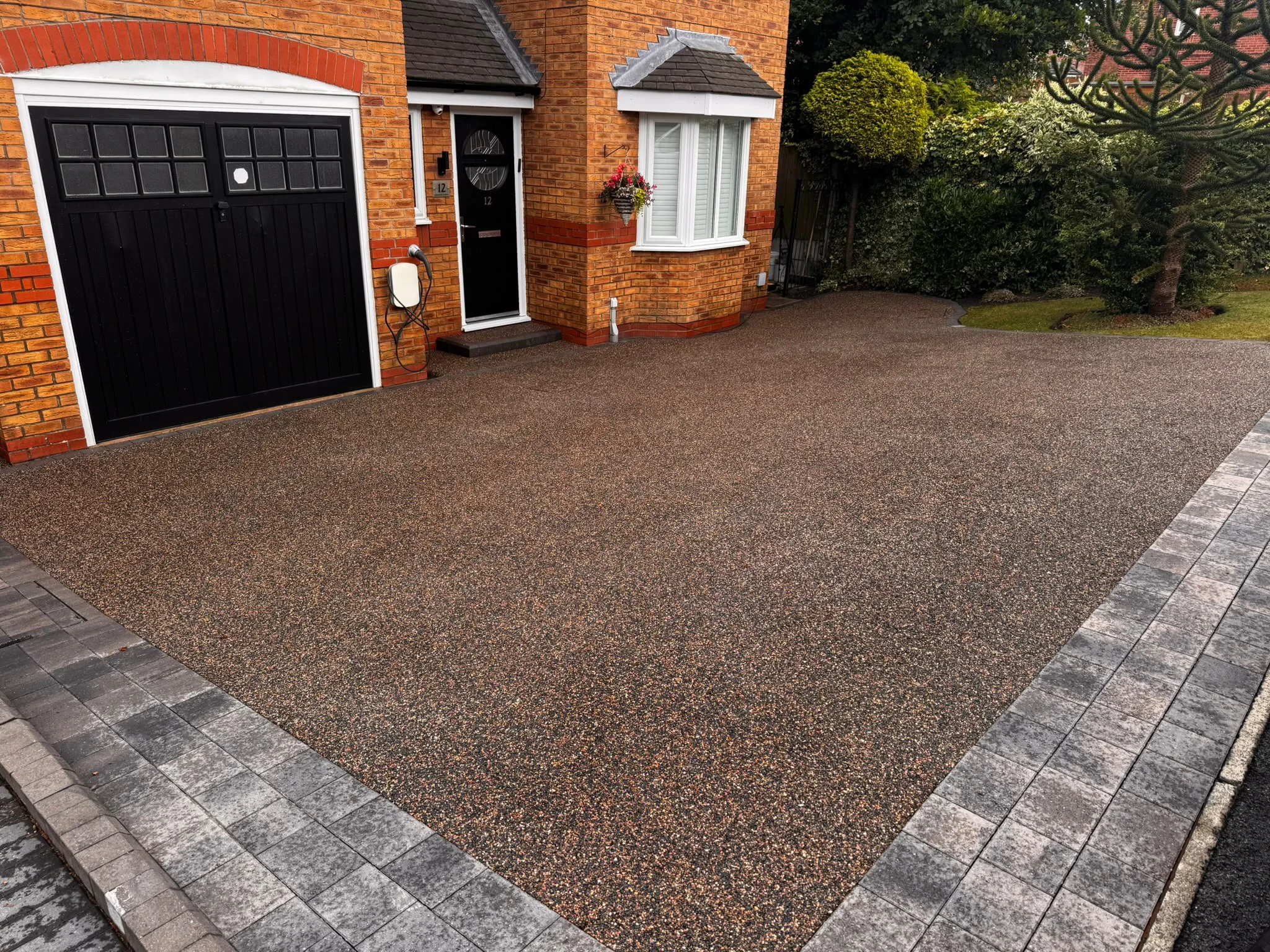 Weathered resin driveway outside a brick home before professional cleaning