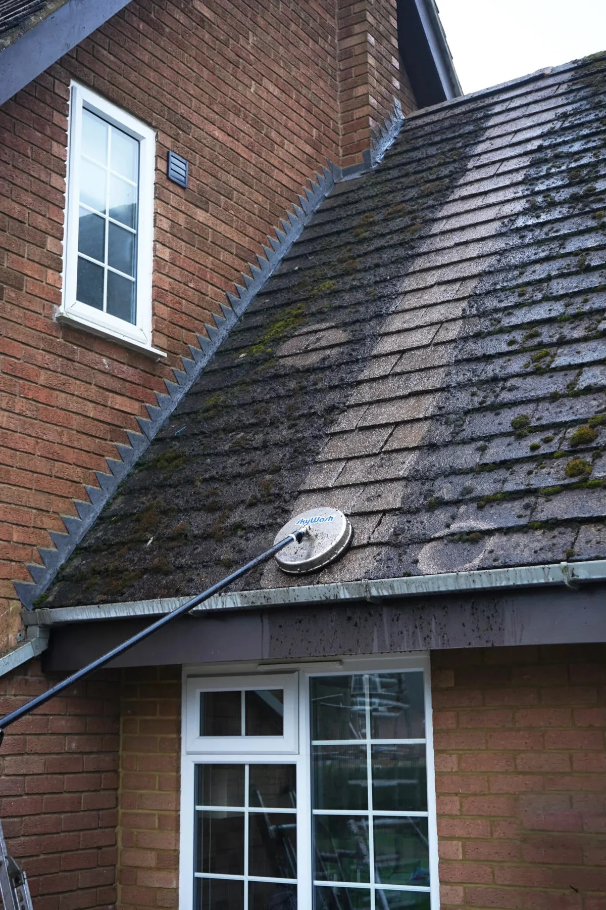 Roof surface cleaner treating a moss-covered tiled residential roof