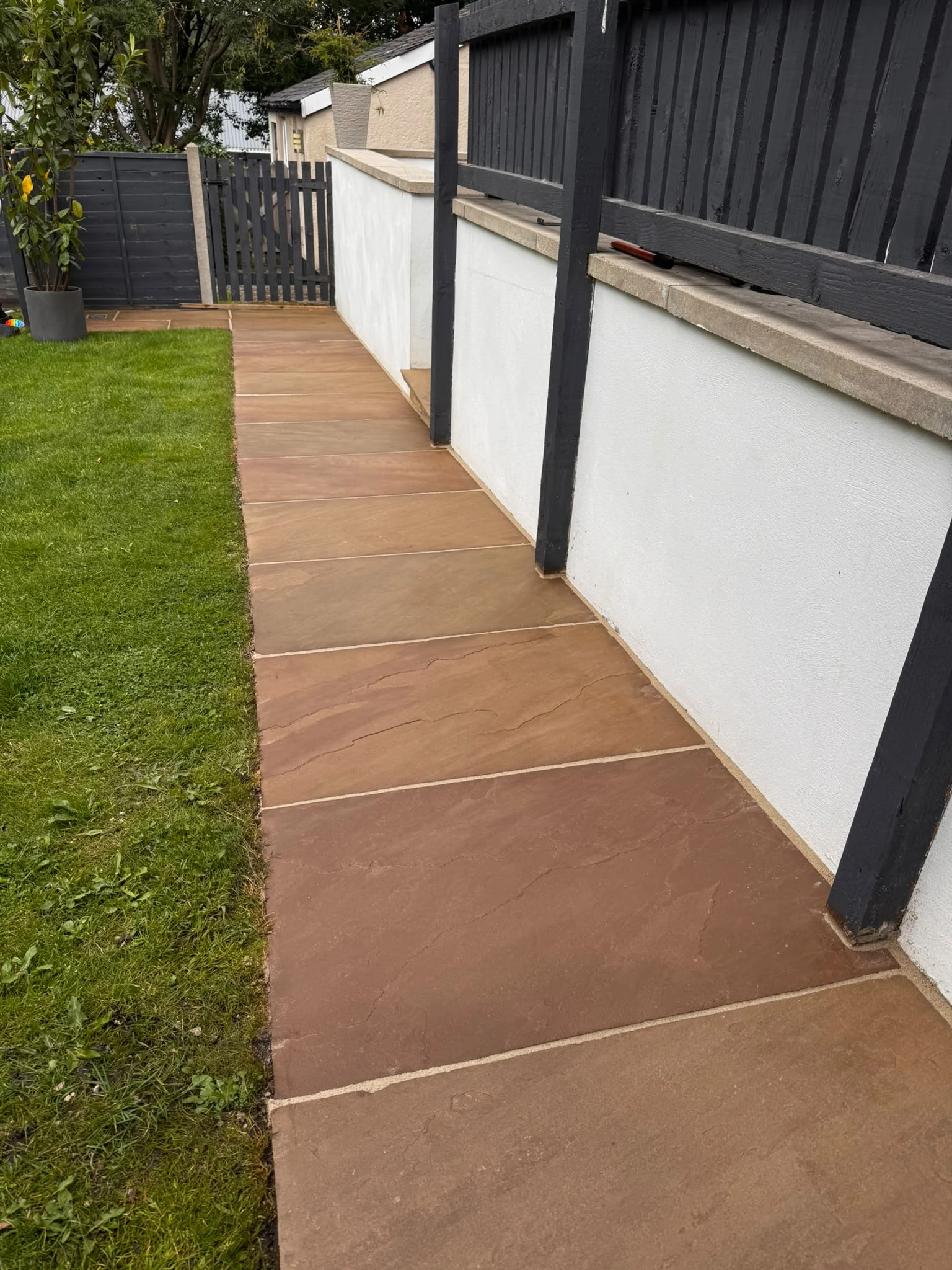 Cleaned stone side path beside a lawn after professional exterior cleaning